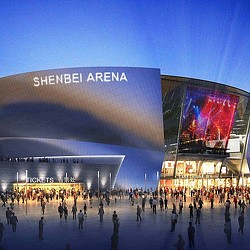 A large crowd of people outside of a building with large screens.