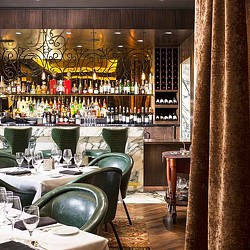 A bar with green chairs and tables.