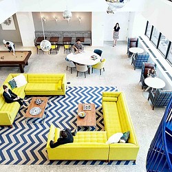 A room with yellow couches and a table with people sitting at it.