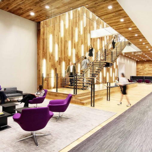 People in a room with chairs and a staircase.