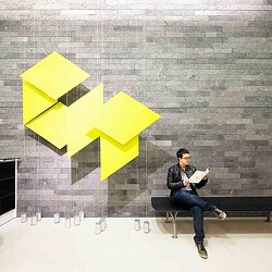 A man sitting on a bench with a paper airplane on his lap.