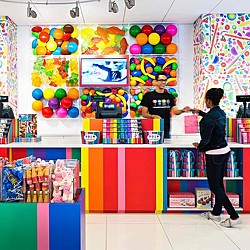 A boy standing in front of a shelf with balloons.