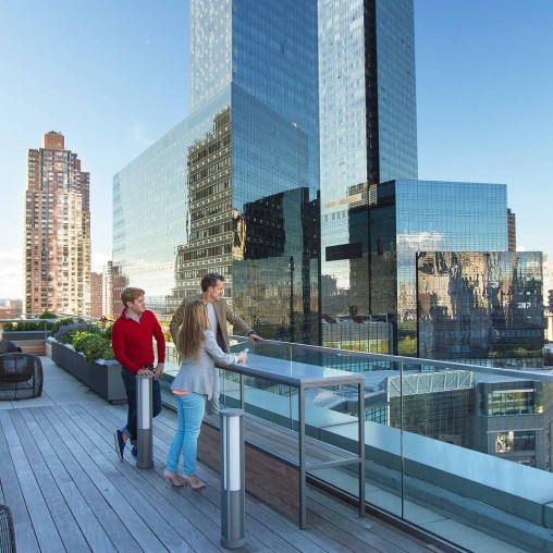A man and woman walking on a bridge over a city.