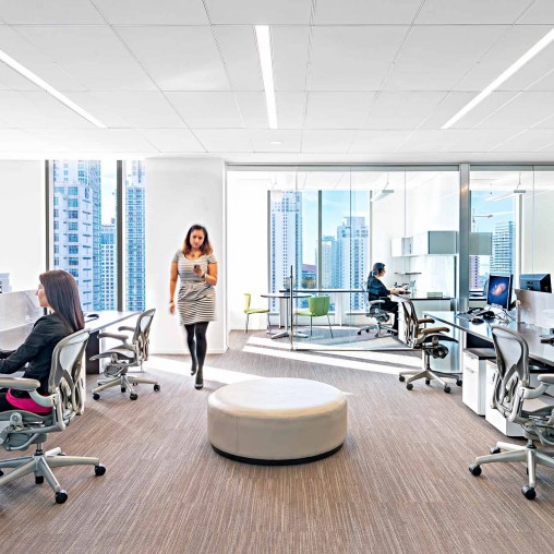 A person standing in a room with people sitting at desks and computers.