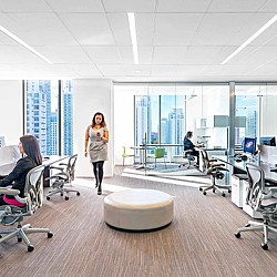 A person standing in a room with people sitting at desks and computers.