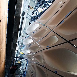 A group of people standing in a room with a large white ceiling.