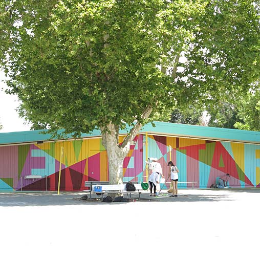 A group of people standing next to a tree and a building.
