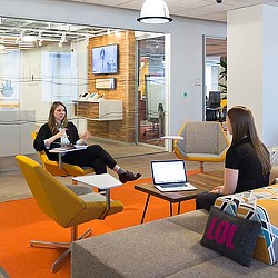 A couple of women sitting at a table with laptops.
