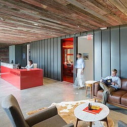 A person sitting on a couch in a room with a person standing.