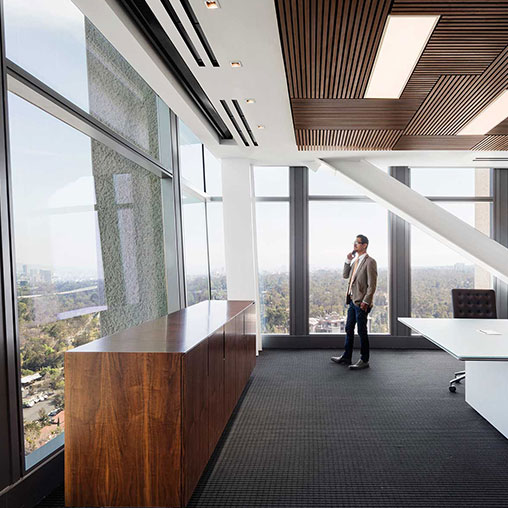 A person standing in a room with large windows.