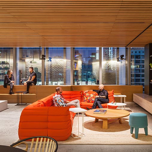 A group of people sitting on a couch in a room with windows.