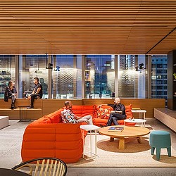 A group of people sitting on a couch in a room with windows.