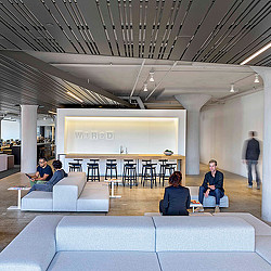 A group of people sitting in a room with a large screen.