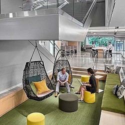 A couple of people sitting in a room with a green floor and a large green wall with a.