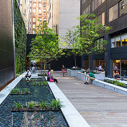 A group of people sitting on a bench in a courtyard.