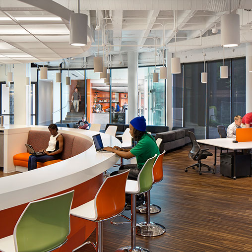 A group of people sitting in a room with tables and chairs.