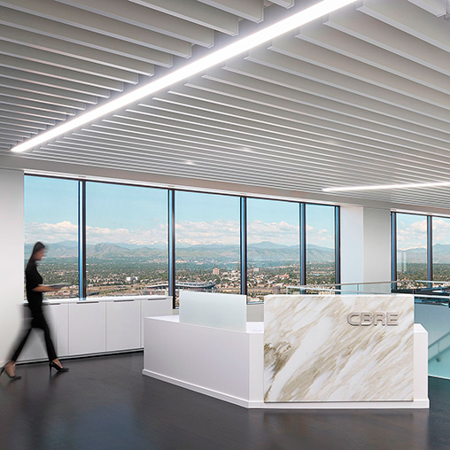 A person standing in a room with large windows and a large white table.