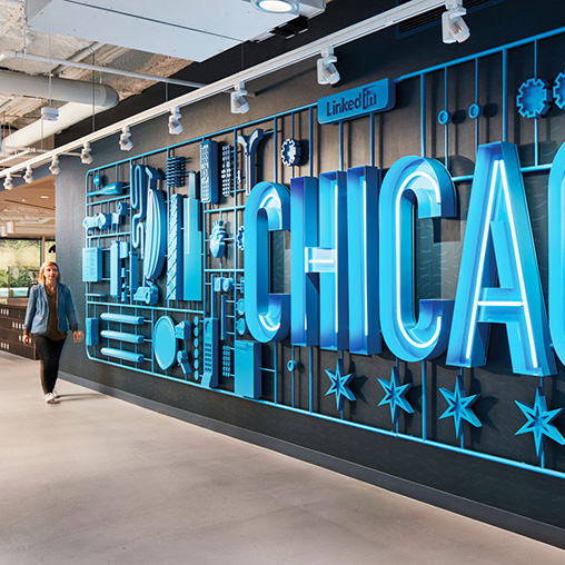 A person standing next to a wall of blue and white letters.