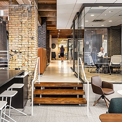 A room with a brick wall and a couple people sitting at tables.