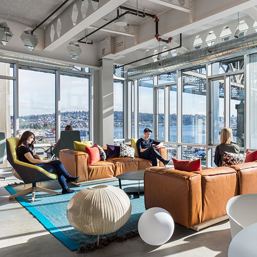 A group of people sitting on a couch in a room with large windows.
