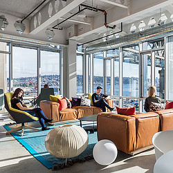 A group of people sitting on a couch in a room with large windows.
