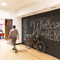 A person walking by a black board with writing on it.