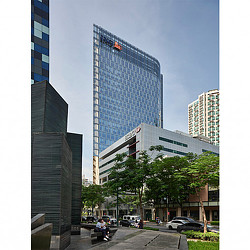 A person sitting on a bench in front of a tall building.