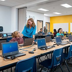 A group of people sitting at a table with laptops.