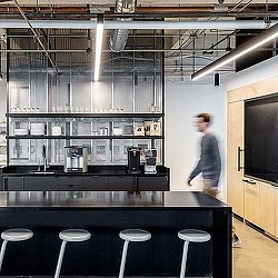 A person standing in a room with stools and a counter.