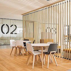 A room with a table chairs and a wall with a curtain.