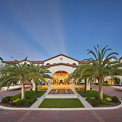 A building with palm trees and a fountain in front of it.