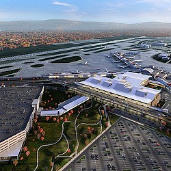 A large group of people at a dock with boats and a body of water in the background.