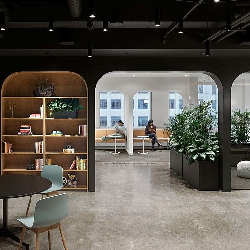A couple of people sitting on a bench in a room with a large window.