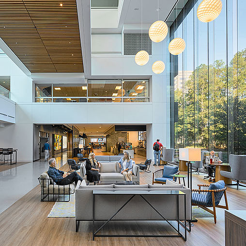 A group of people sitting in a room with a large glass wall.