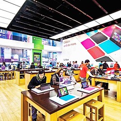 A group of people in a room with tables and computers.