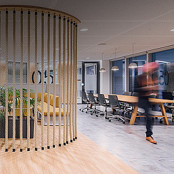 A person walking in a room with a table and chairs.