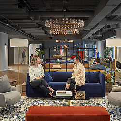 A couple of women sitting on a couch in a mall.