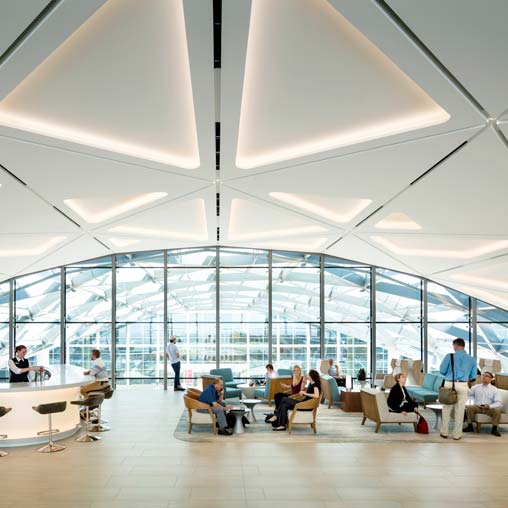 A group of people sitting in a room with large windows.