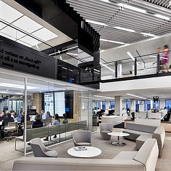 A group of people sitting in a large room with white tables and chairs.