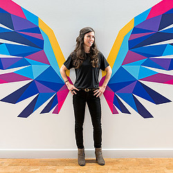 A person standing in front of a wall with a flag.