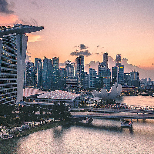 A city skyline with a plane flying over a body of water.