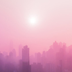 A city skyline with the sun in the background.