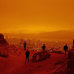 A group of people standing on a hill with a city in the background.