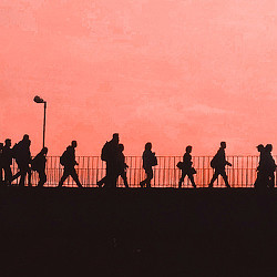 A group of people walking on a road at sunset.