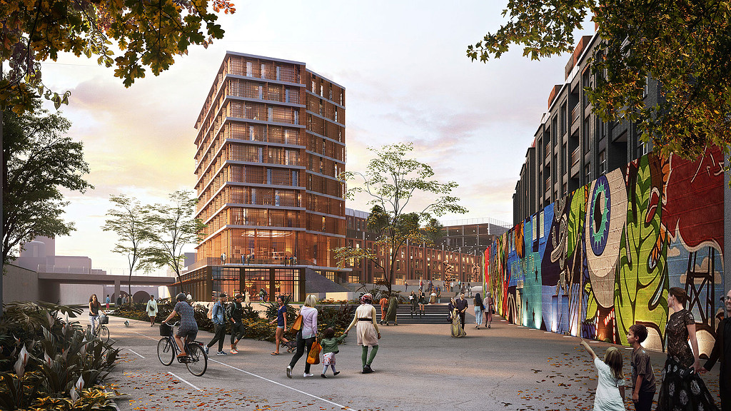 A group of people walking on a street with buildings on either side.