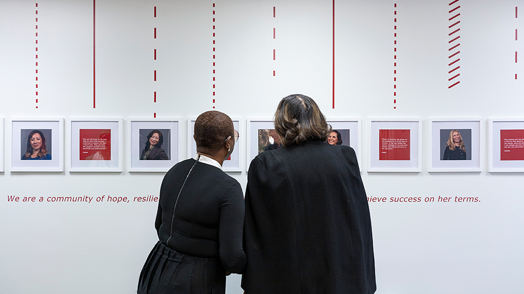 A man and woman looking at pictures on a wall.