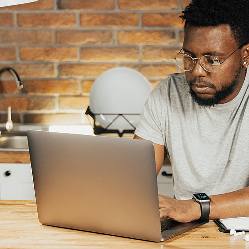 A man sitting at a table with a laptop.