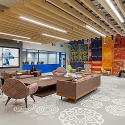 A person sitting on a couch in a room with a large screen.