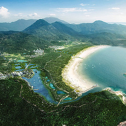 A beach with a body of water by it and mountains in the background.