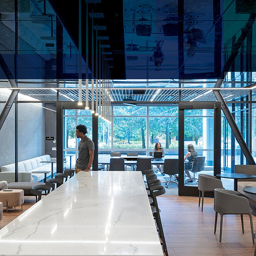 A room with a large glass wall and a table with chairs and people.